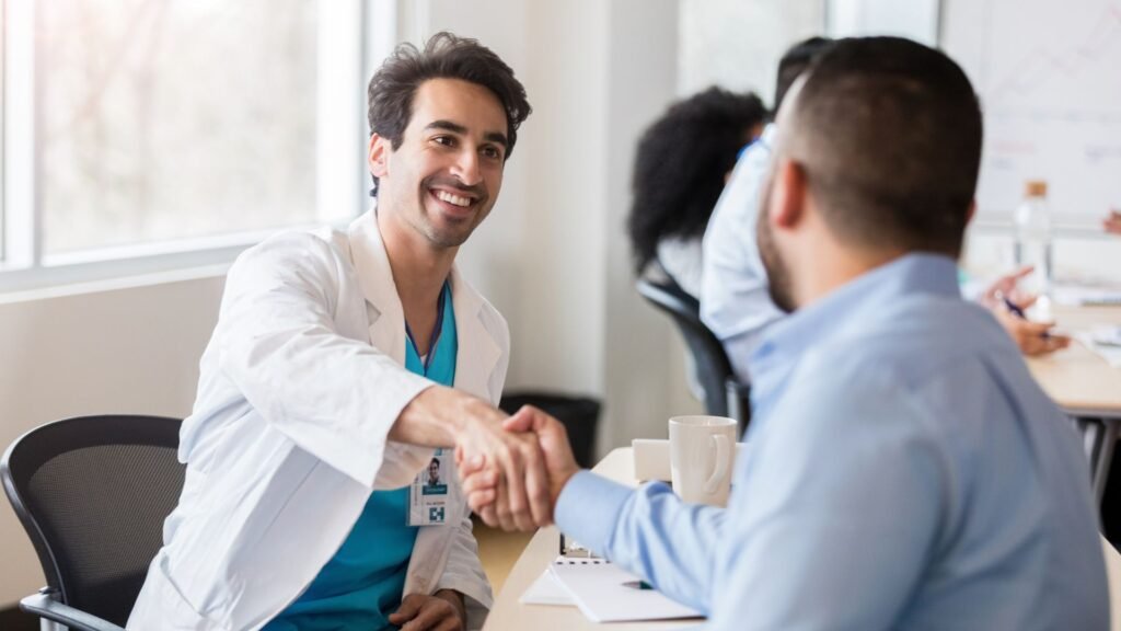 Médico investigador sonriente estrechado la mano de su paciente